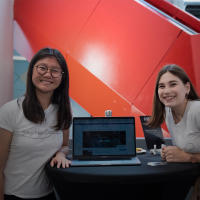 Two students standing beside a laptop