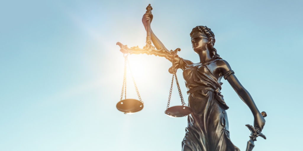 image of a statue representing lady justice holding the scales of justice, holding a sword and her eyes are covered in a cloth