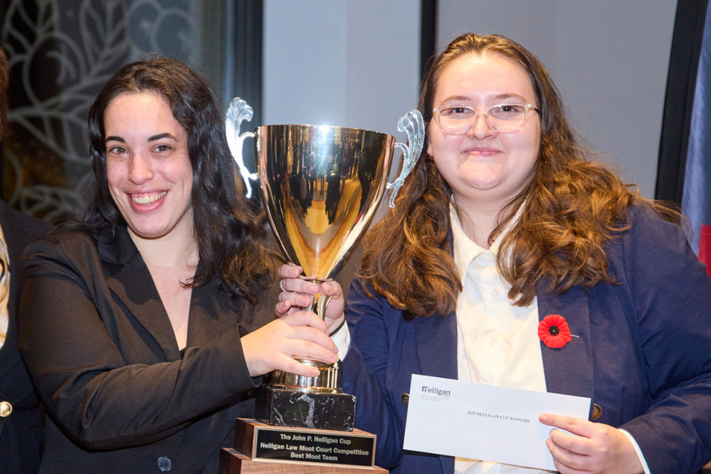 Deux jeunes femmes tiennent un grand trophée.