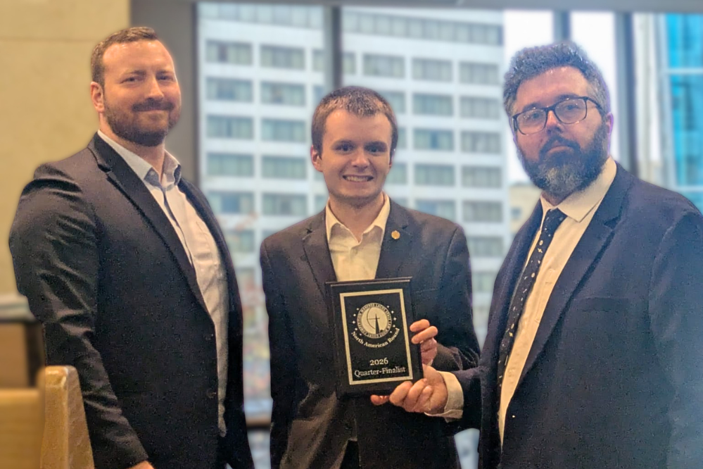 Trois hommes en costume. L'un d'eux tient une plaque.