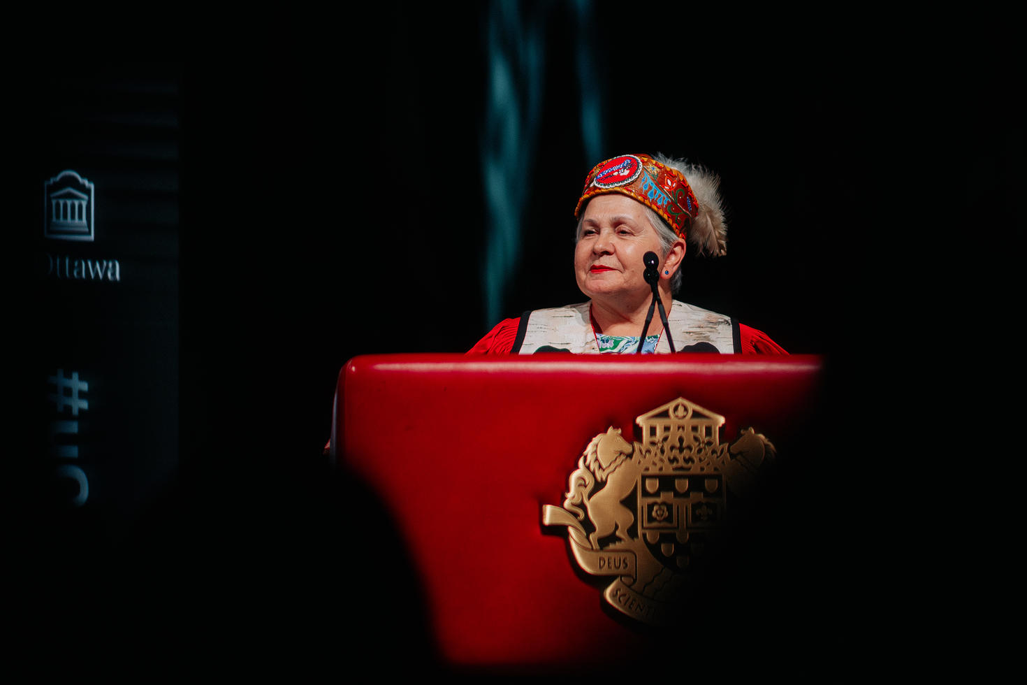 Femme debout près d’un pupitre, prononçant un discours au microphone.