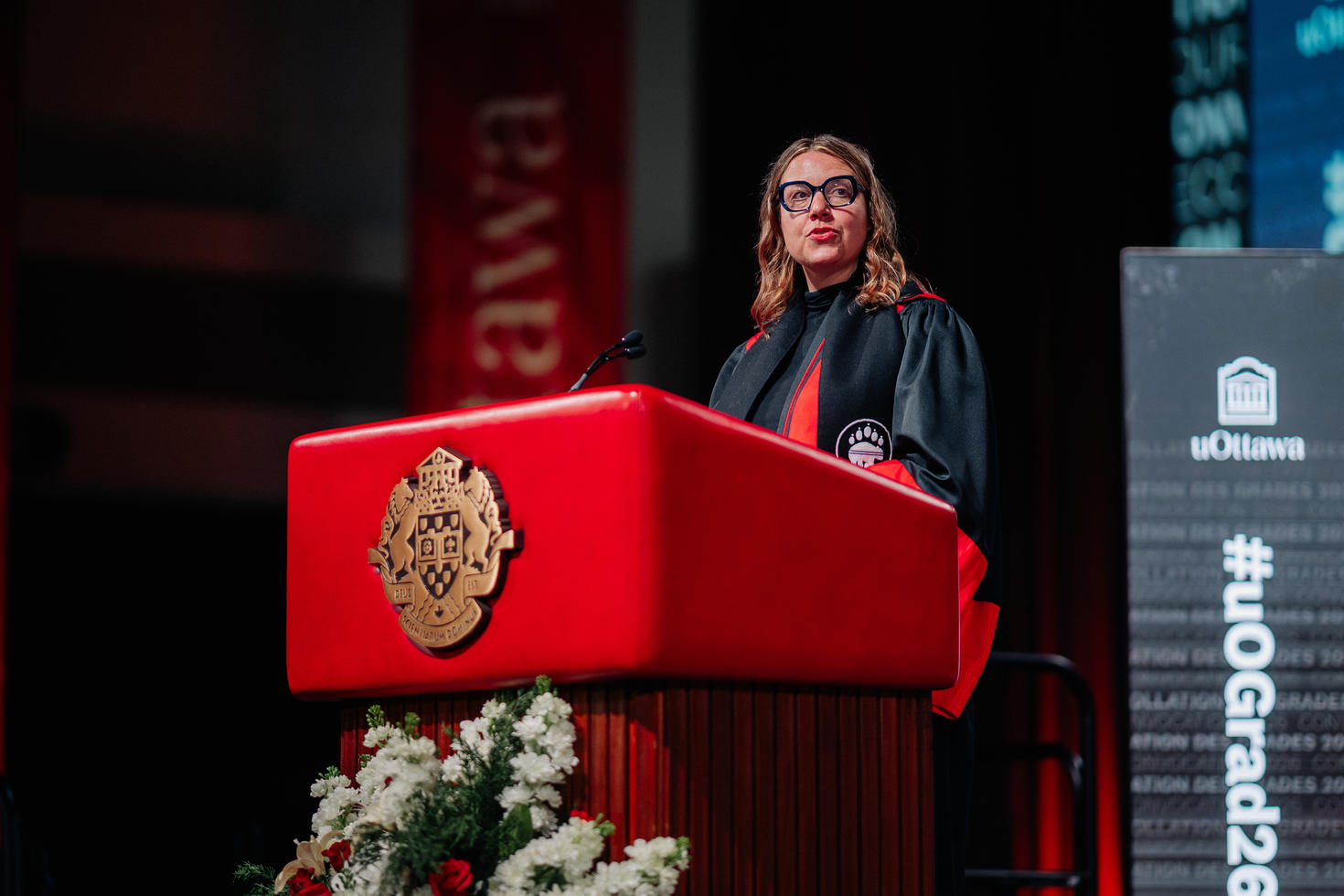 Femme prononçant un discours à un podium lors d’une cérémonie de collation des grades.