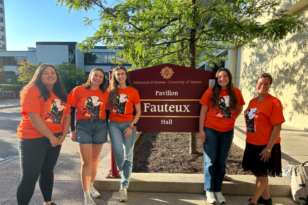 Cinq étudiants vêtus de t-shirts orange ont posé à côté du panneau « Loi défectueuse ».