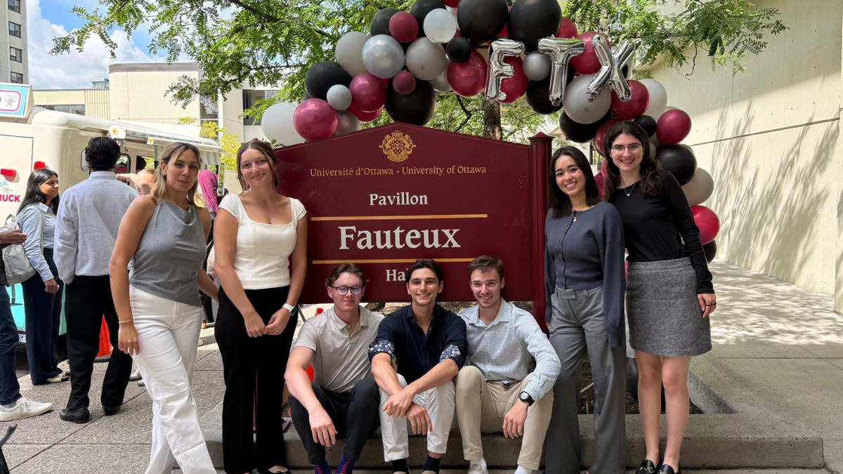 Image de 7 étudiants posant devant l’enseigne Fauteux avec des ballons.