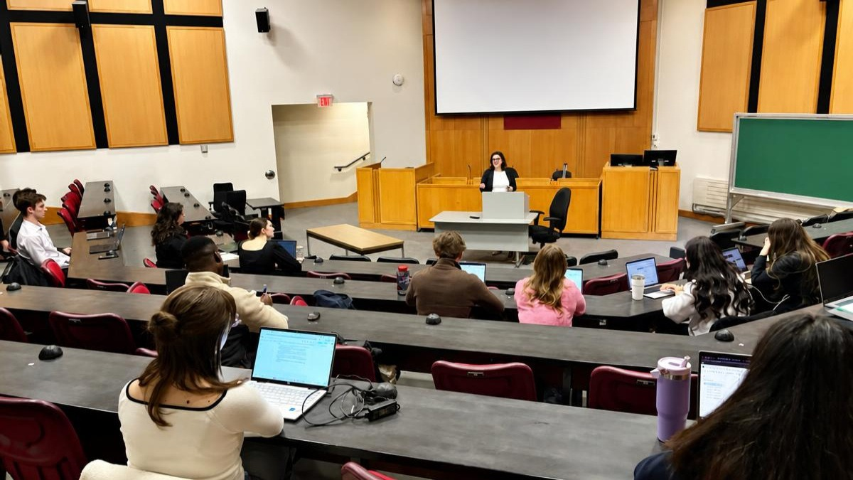 Image d’étudiants dans un amphithéâtre écoutant une conférencière.