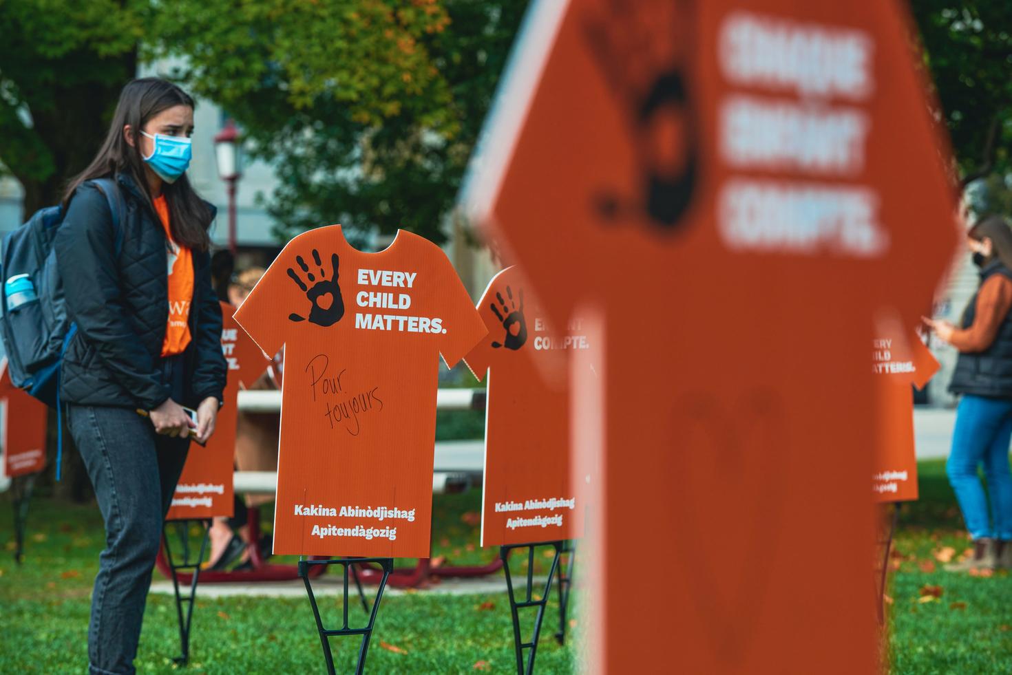 Étudiant debout près du t-shirt orange planté dans l’herbe