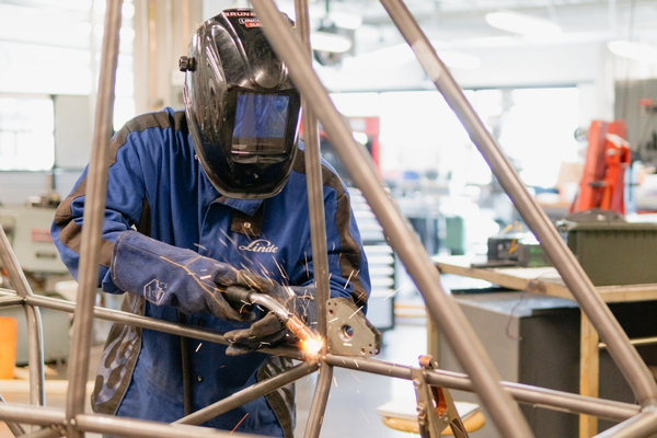 Un étudiant en train de souder dans un atelier.