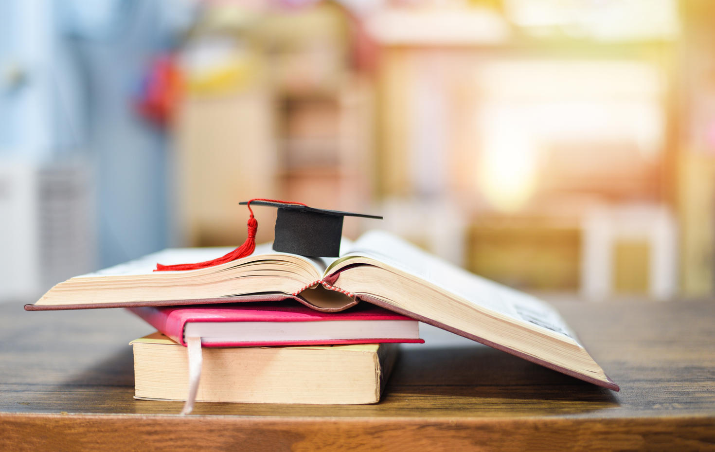 Chapeau de diplômé posé sur une pile de livres