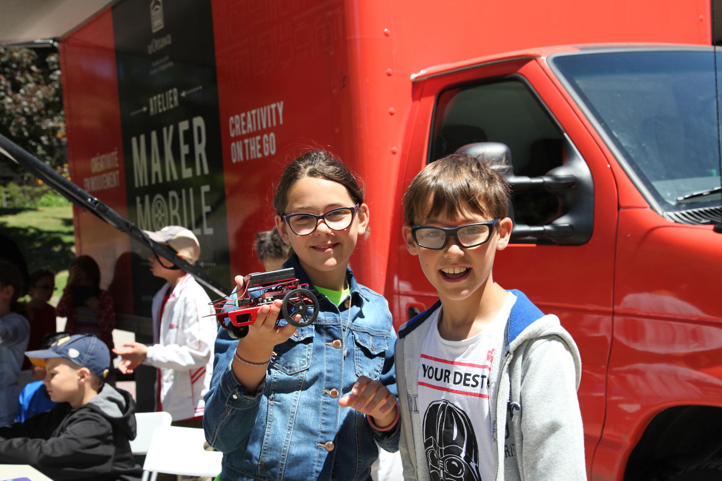 Deux jeunes étudiants devant la voiture atelier mobile MakerMobile.