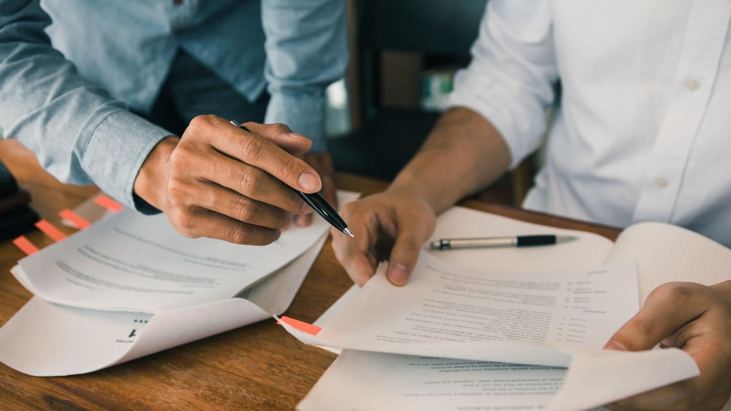 Mains de deux étudiants comparant leurs notes.