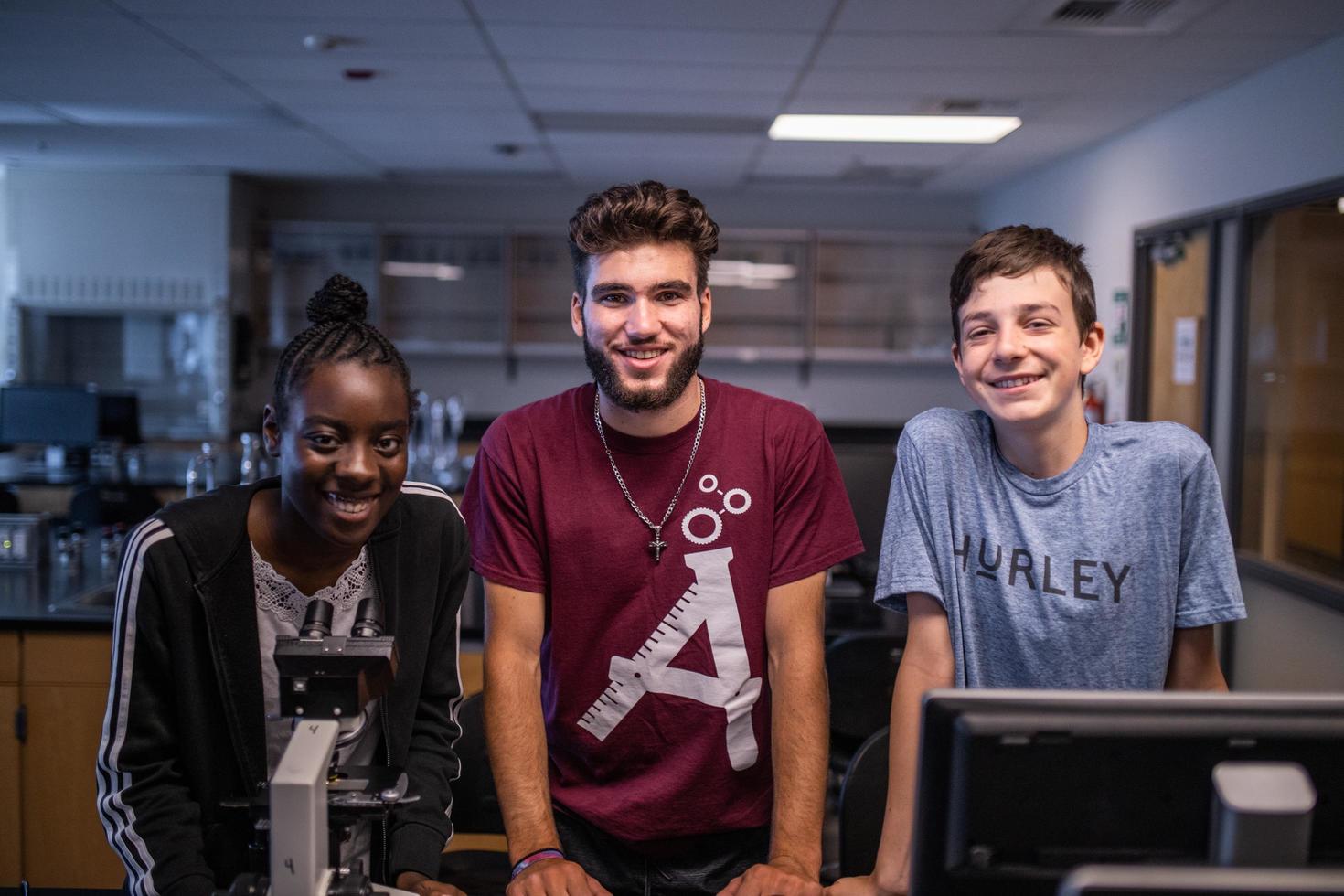 Trois jeunes souriants dans un laboratoire.