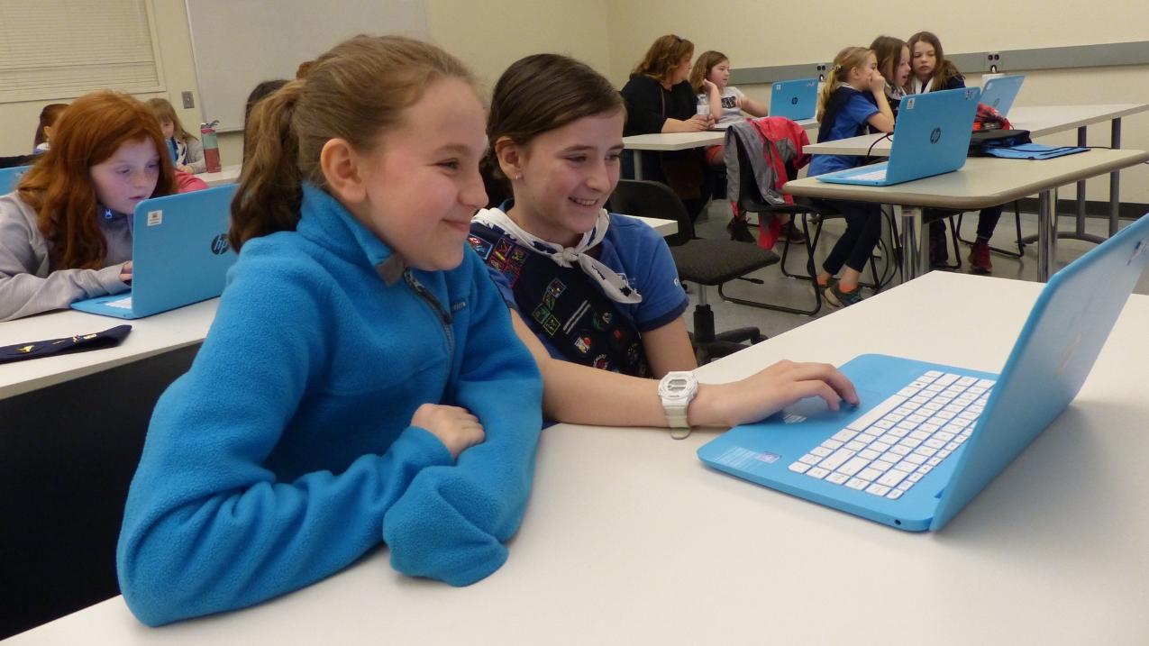 Two girls smiling in front of a computer.