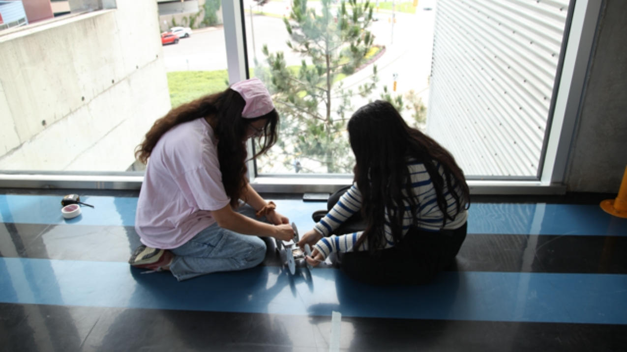 Deux filles travaillant sur un véhicule petit.