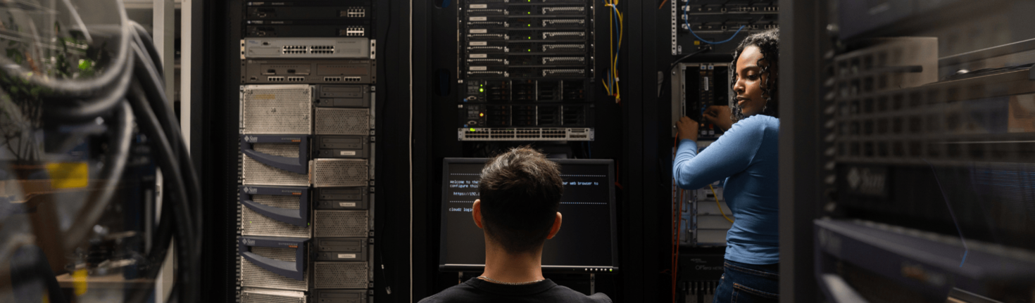 Une étudiante et un étudiant travaillent dans un laboratoire informatique avec serveurs.