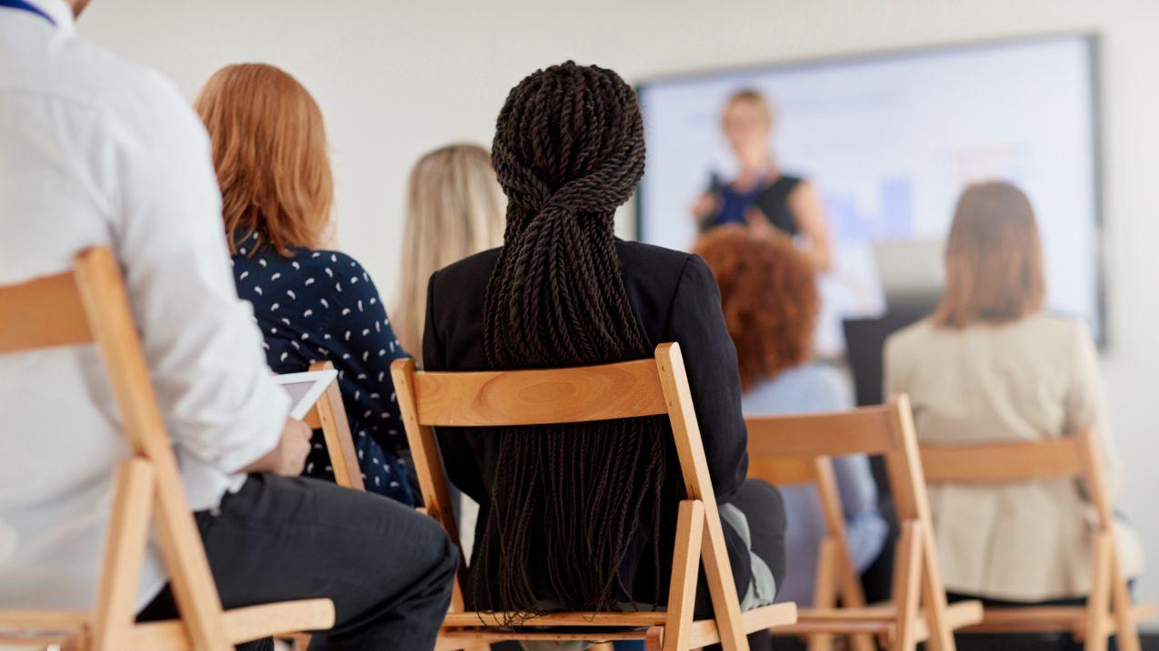 Groupe de personnes assises, écoutant une personne qui fait une présentation. Posture fantastique.