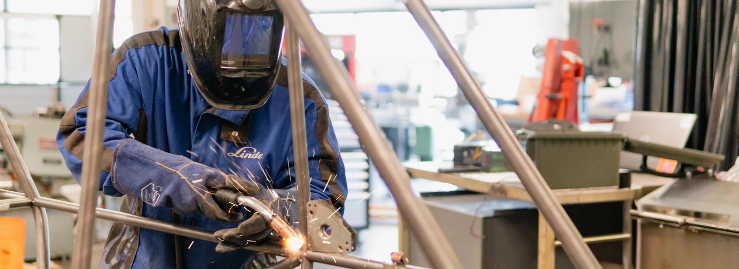 Un étudiant en train de souder dans un atelier.