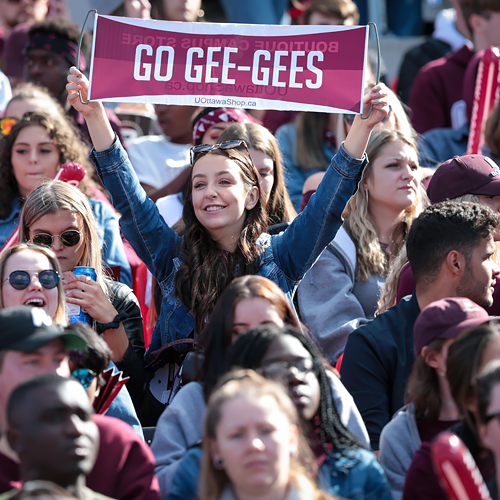 Femme dans la foule tenant une bannière GO GEE GEES