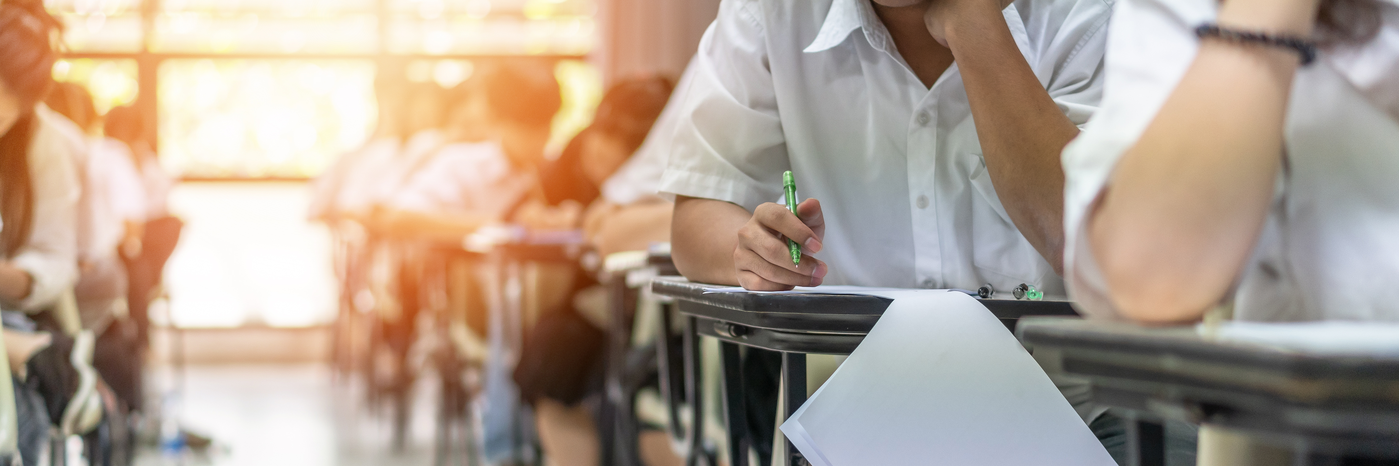 Examen à l'école avec un élève qui passe un test d'admission en classe, qui réfléchit beaucoup, qui écrit une réponse dans une salle de classe d'université, concept d'éducation et de journée mondiale de l'alphabétisation.