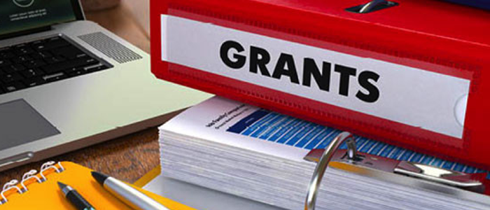 Onglet rouge marqué « GRANTS » au-dessus d’une pile de dossiers et de documents.