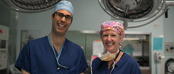 Médecins en blouse, souriant à la caméra dans une salle d'opération.