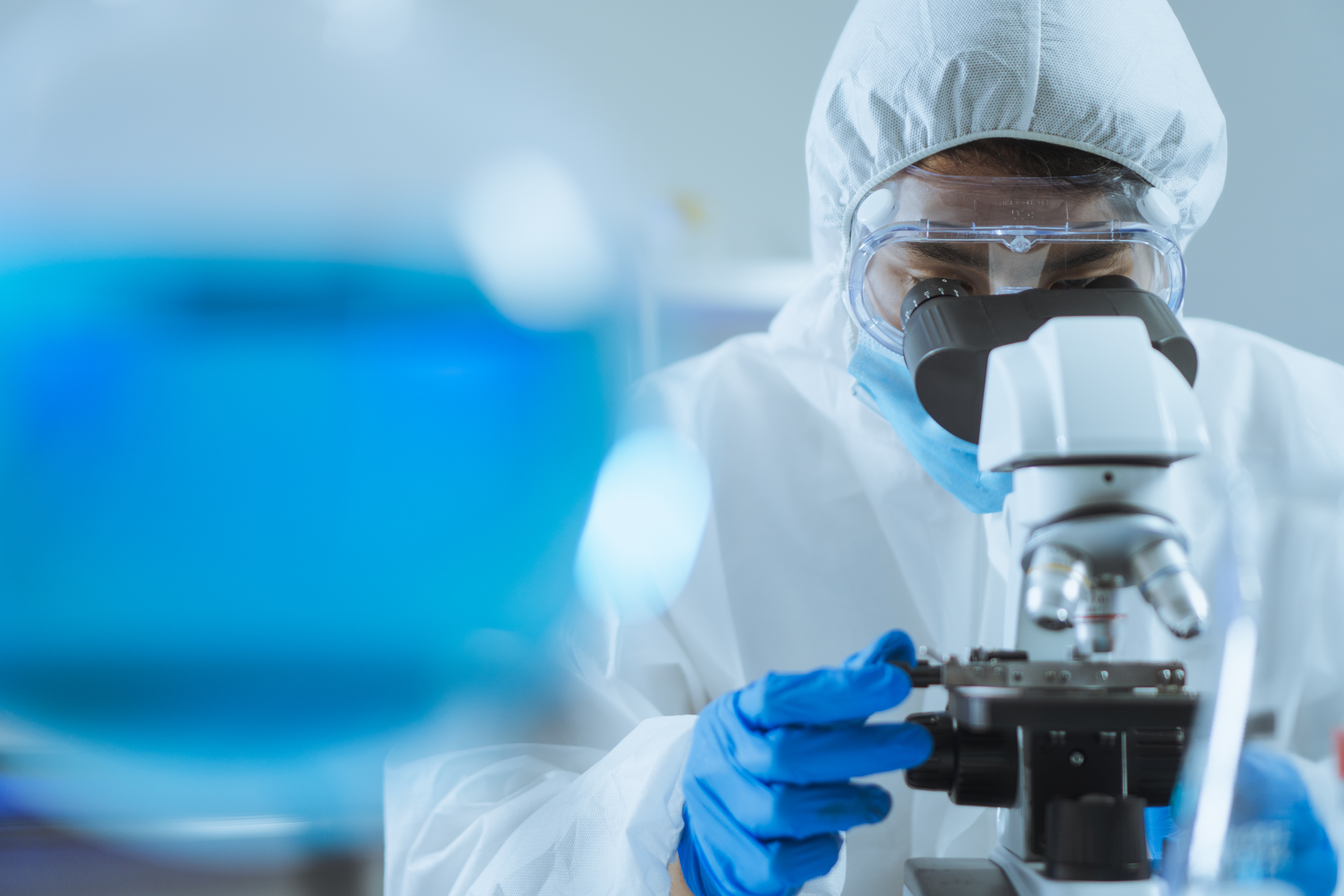 Un jeune homme asiatique, beau scientifique, ajuste la mise au point et utilise un microscope pour observer une cellule biochimique en laboratoire.
