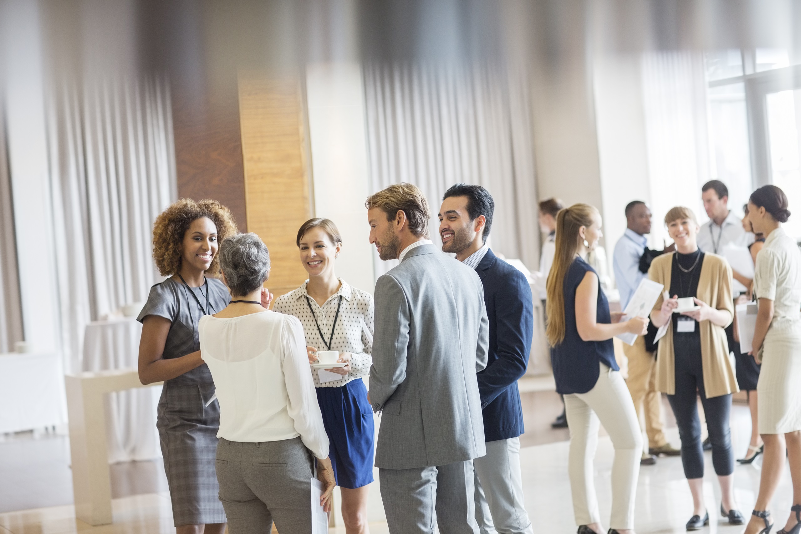 Groupe d'hommes d'affaires dans un hall, souriant et discutant ensemble.