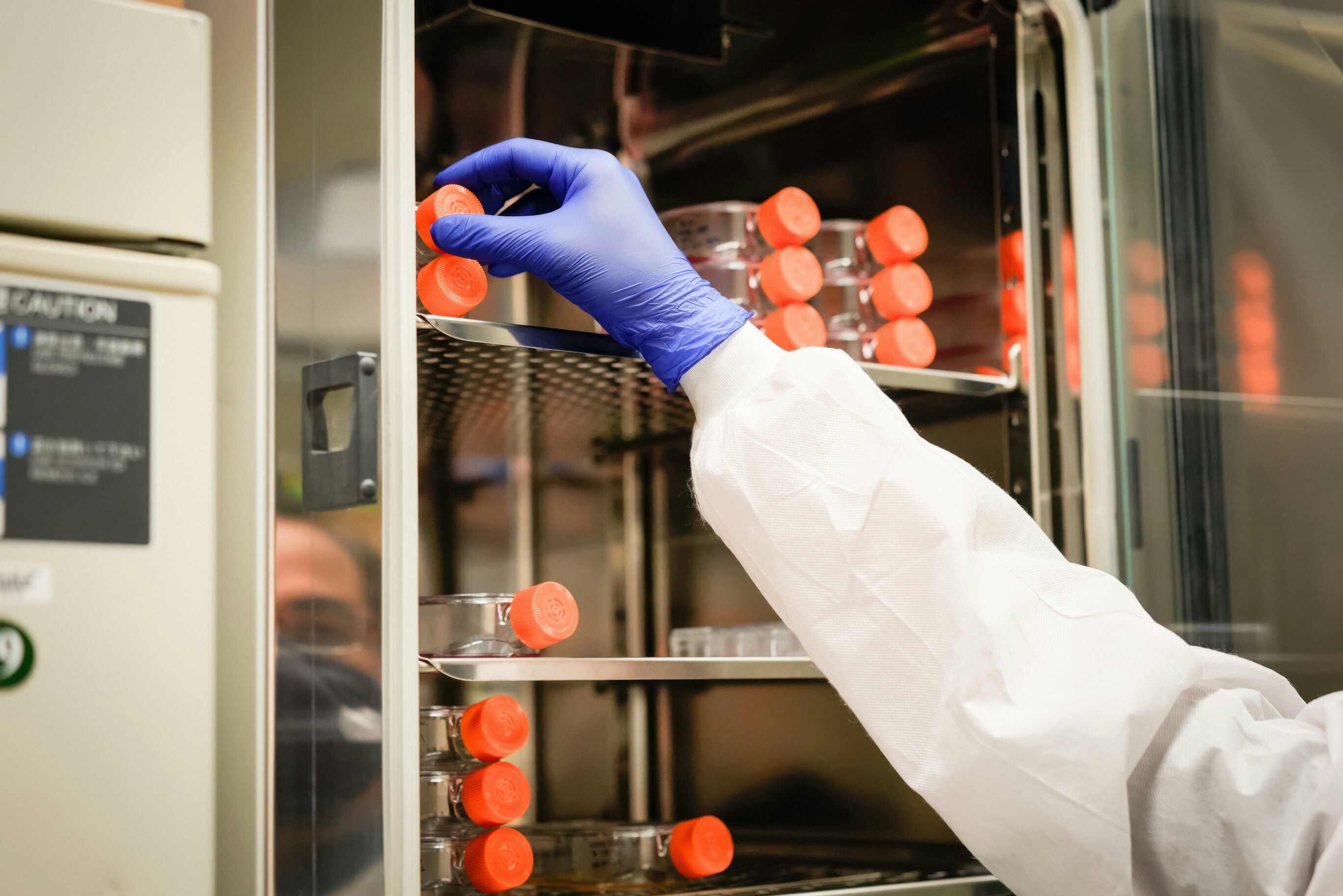 Technicien de laboratoire portant des gants et manipulant des récipients scellés dans une unité de stockage de laboratoire