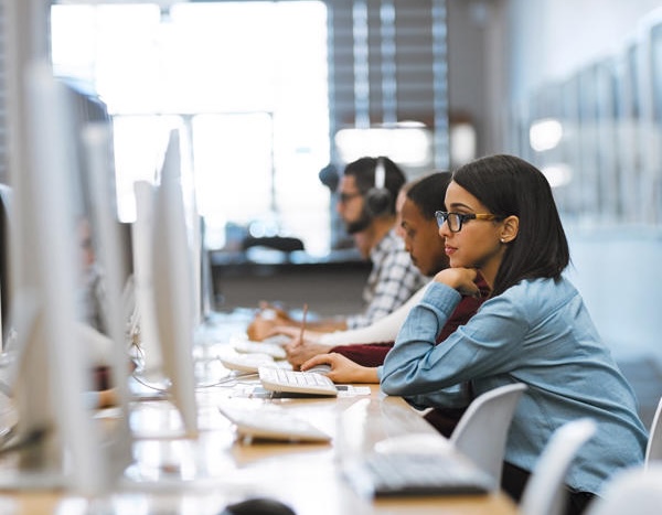 Personnes travaillant à des ordinateurs de bureau dans un environnement moderne de travail ou d’apprentissage.