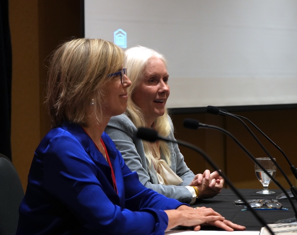 La Dre Liz Muggah, à gauche, vêtue d’un blazer bleu, et la Dre Melissa Forgie, à droite, vêtue d’un blazer gris, prennent la parole lors de la retraite du corps professoral
