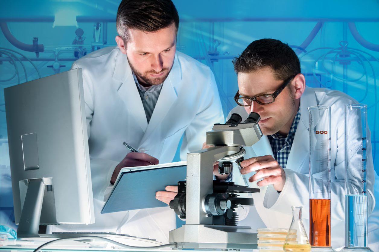 Chercheurs travaillant ensemble dans un laboratoire, examinant de l’équipement et analysant des données à un poste de travail.