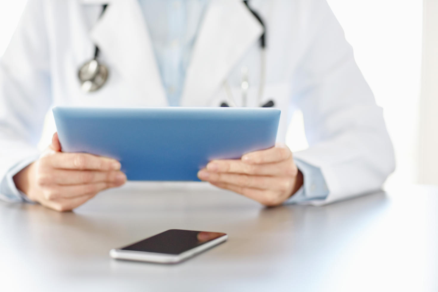 Médecin tenant une tablette numérique avec un téléphone intelligent
