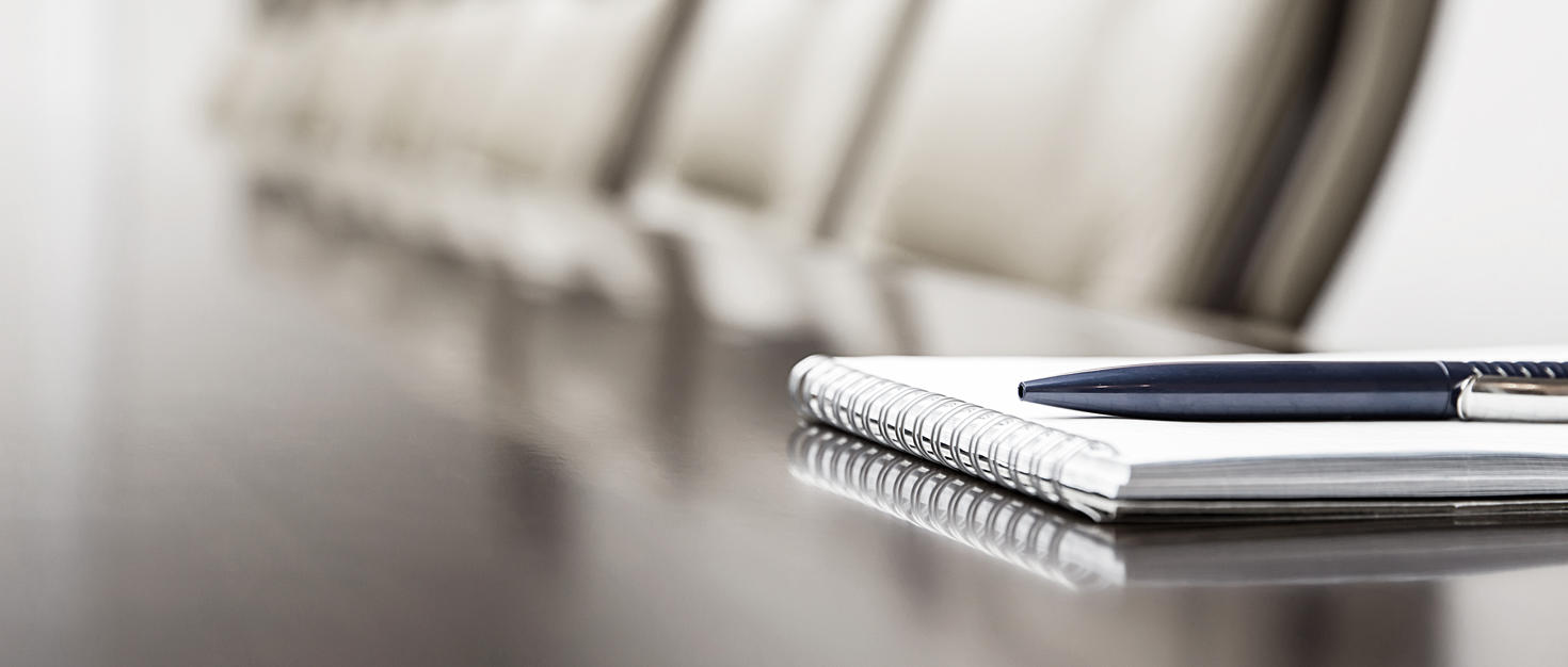 Gros plan sur un bloc-notes posé sur une table dans une salle de conférence vide