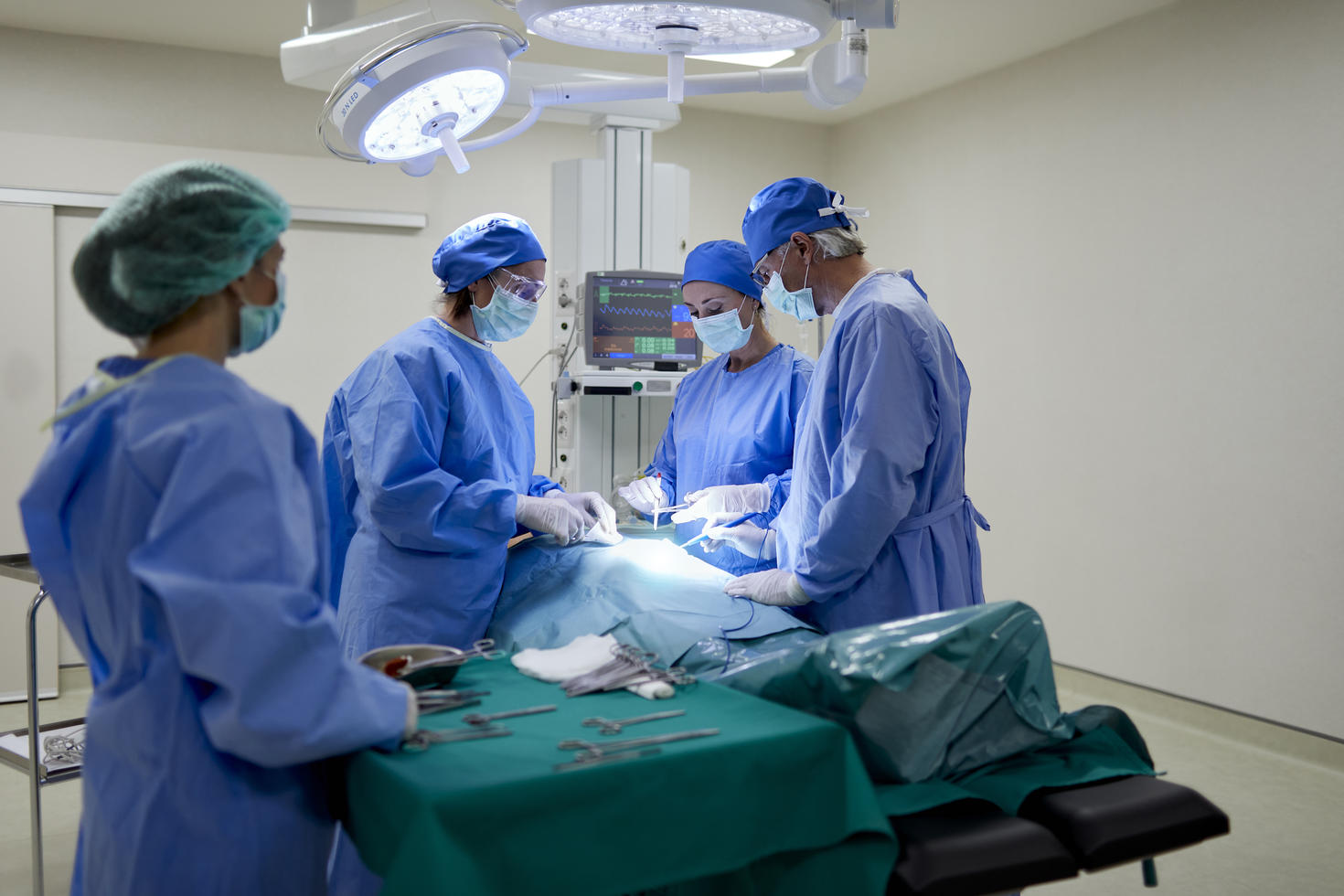 Vue par-dessus l'épaule d'une infirmière assistant une équipe de chirurgiens
