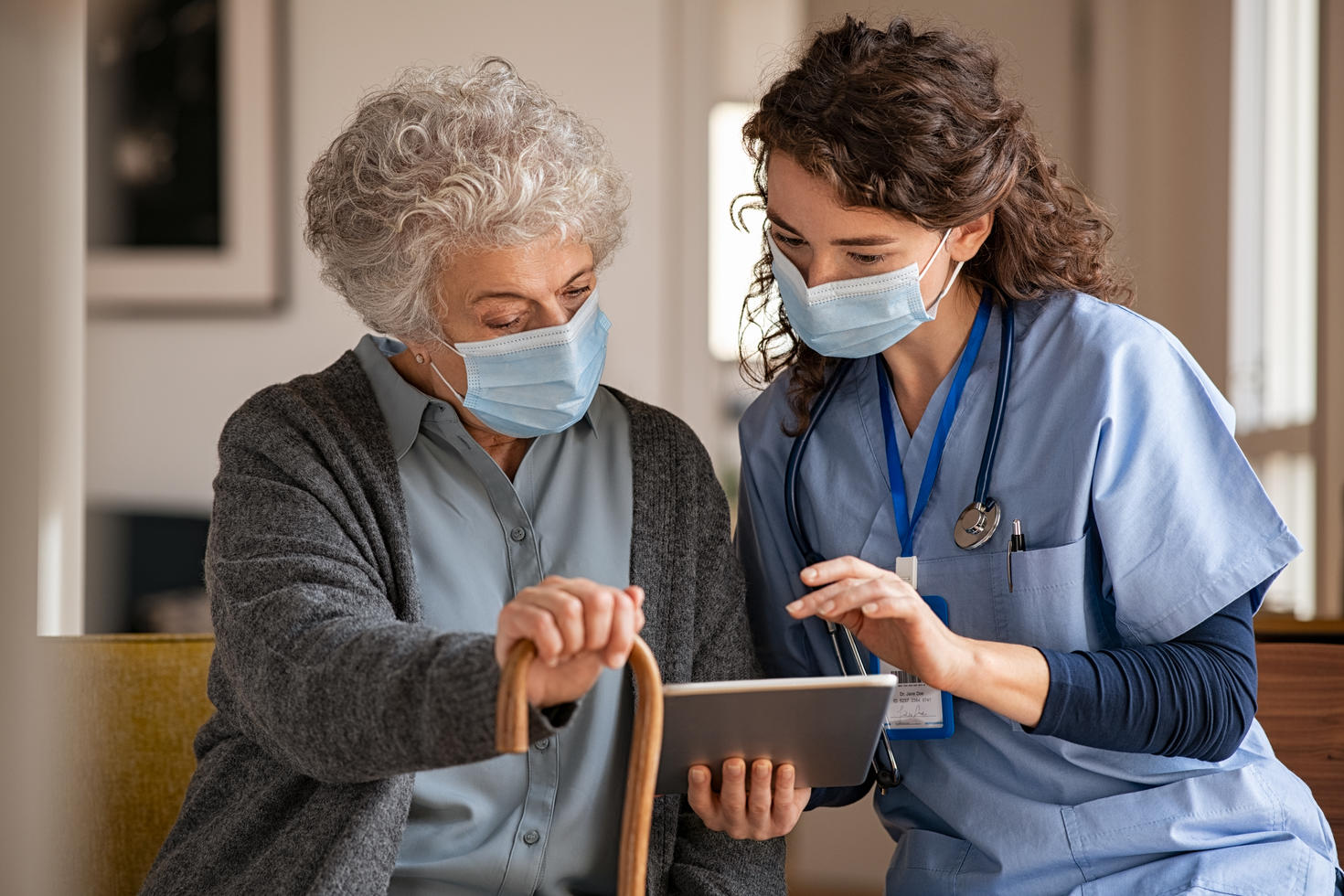 Femme âgée et infirmière utilisant une tablette numérique à domicile lors d'une consultation
