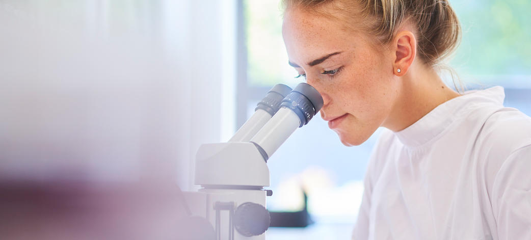 Un scientifique observe un échantillon au microscope dans un laboratoire.