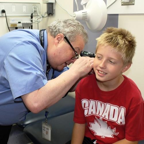 Un médecin utilise un instrument pour vérifier les oreilles d'un jeune homme.
