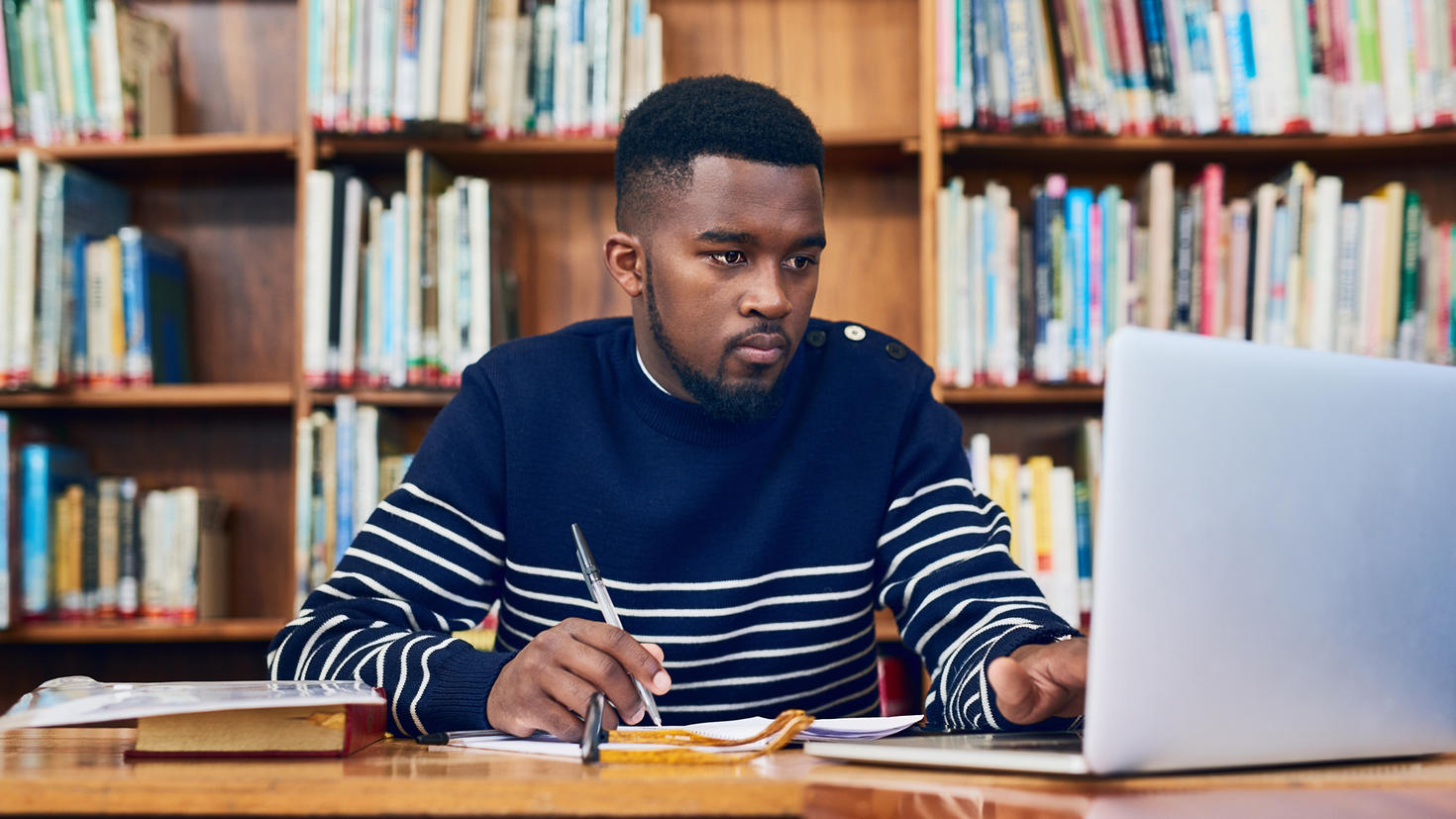 Étudiant noir faisant ses devoirs dans la bibliothèque de l'école.
