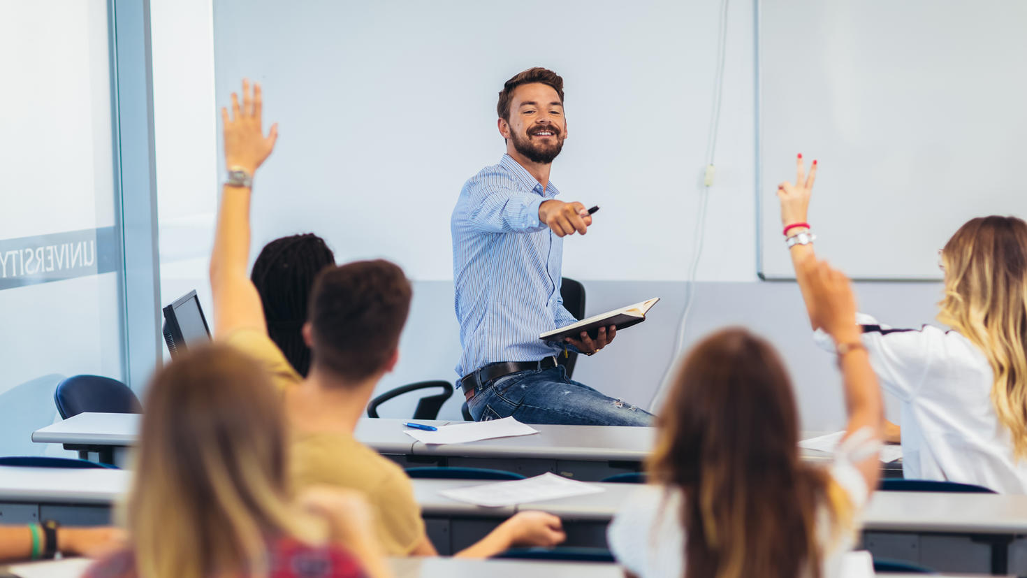 Enseignant assis sur un bureau et répondant à des questions