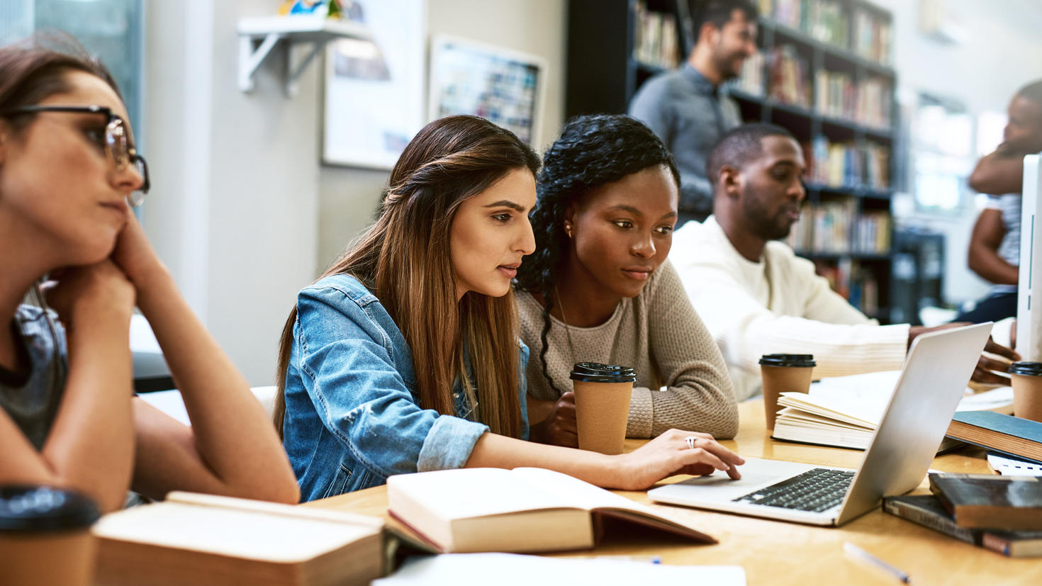 Photo de deux jeunes femmes utilisant un laptop dans une biblitohèque d’université