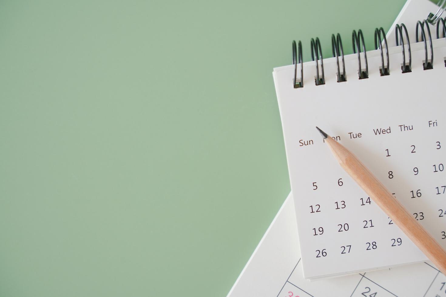 vue de dessus d'un calendrier blanc et d'un crayon brun taillé sur fond vert