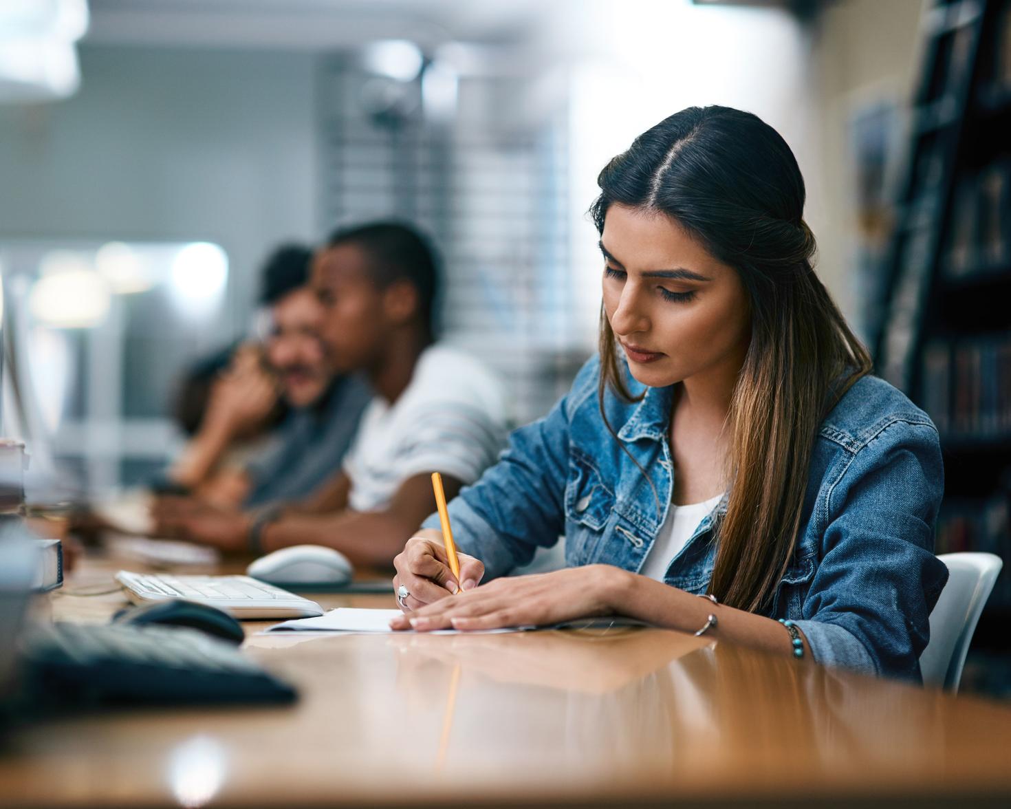 Une étudiante écrit sur un cahier à l'aide d'un crayon