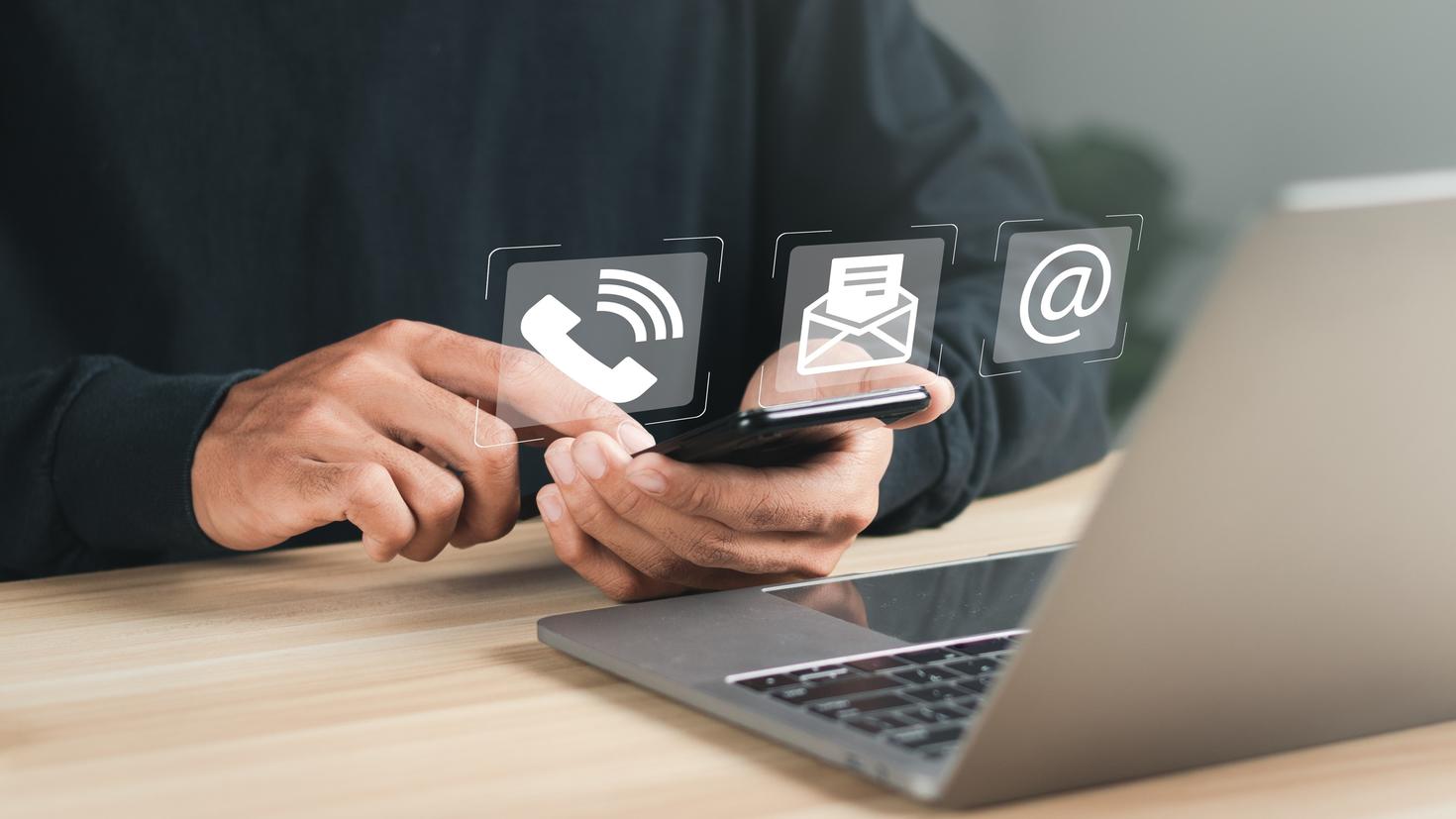 Homme utilisant un ordinateur portable et un téléphone intelligent avec des icônes de contact à l’écran virtuel