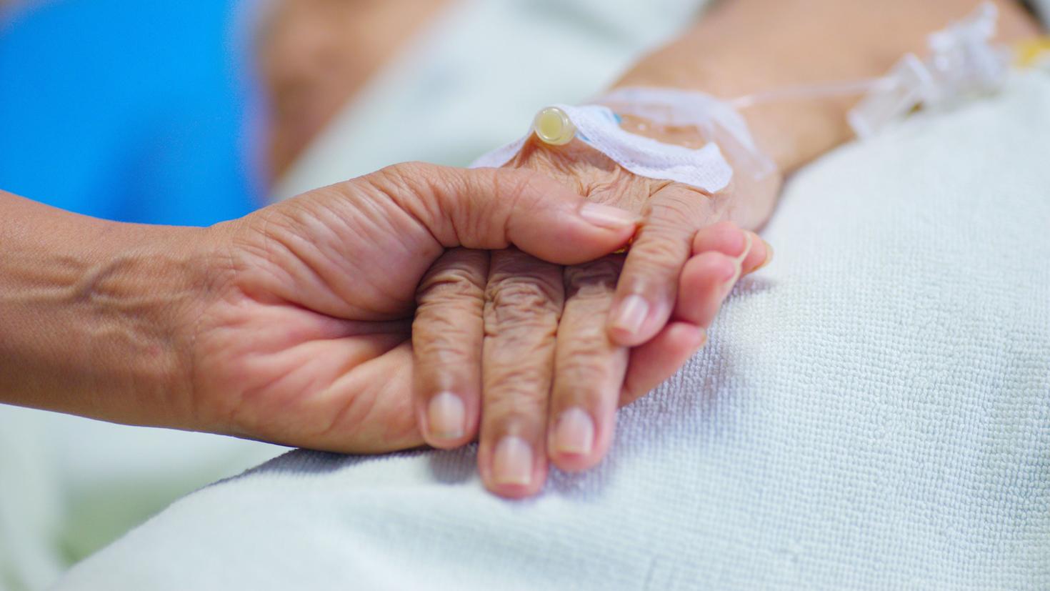 Un proche tenant la main d'un patient