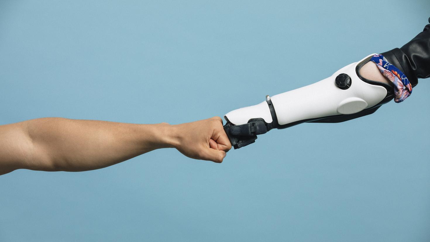Un bras humain et un bras robotique se frappant le poing