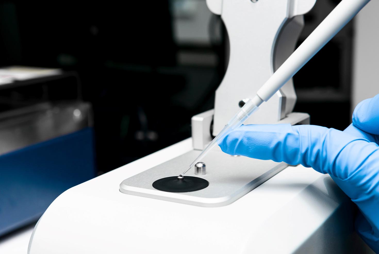 Scientifique chargeant un échantillon sur le piédestal bas du NanoDrop dans le laboratoire.