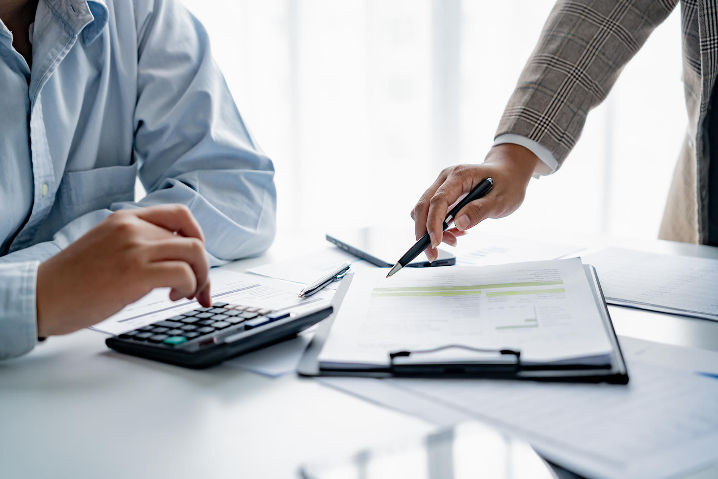 Deux personnes travaillant avec une calculatrice et des documents financiers.