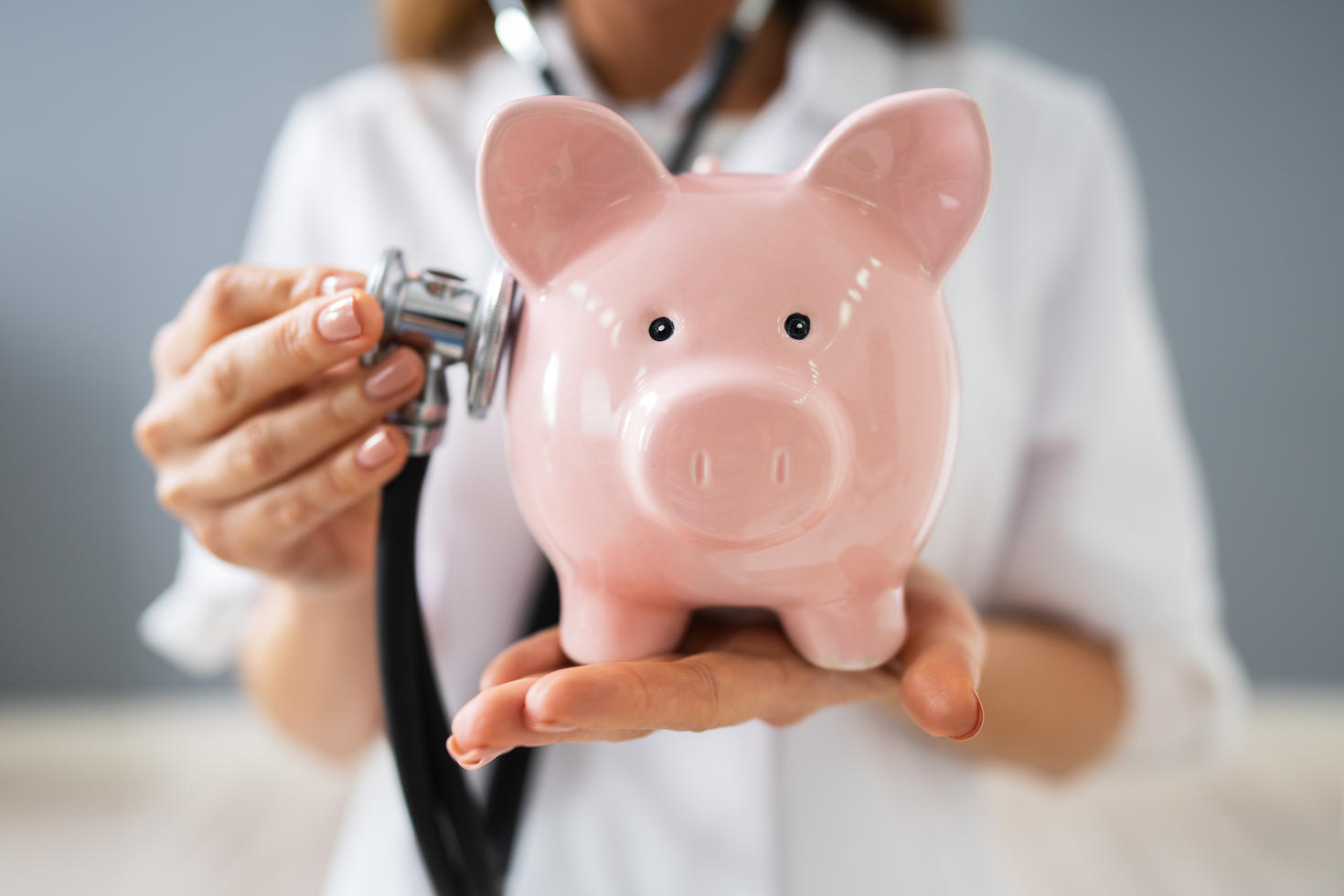 Vue rapprochée d’une jeune femme médecin tenant une tirelire dans une clinique