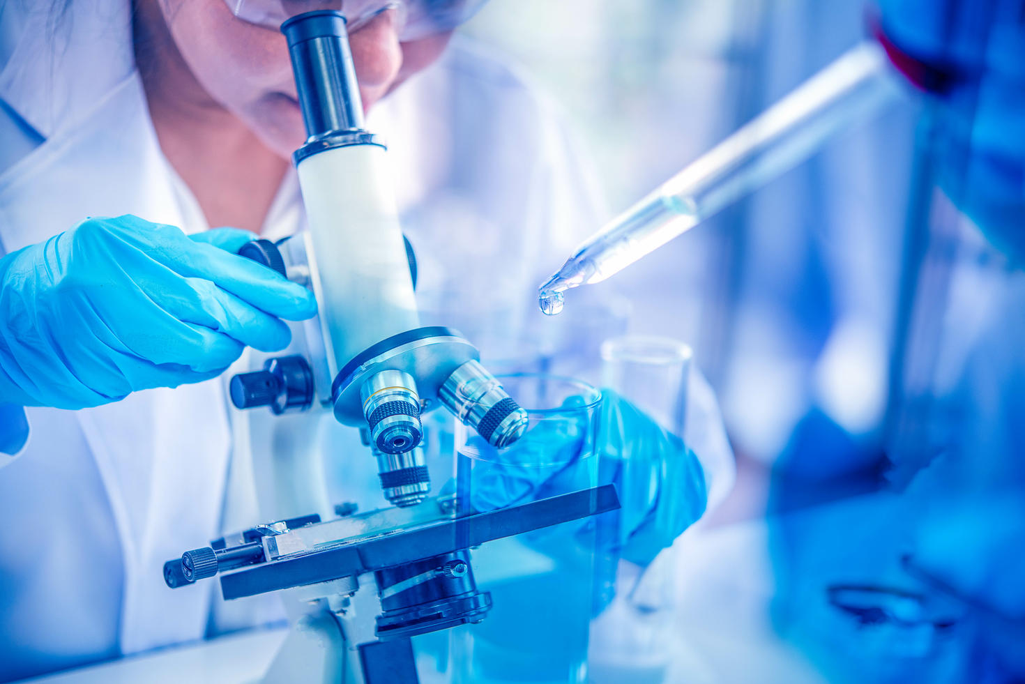 Femme scientifique observant au microscope dans un laboratoire.