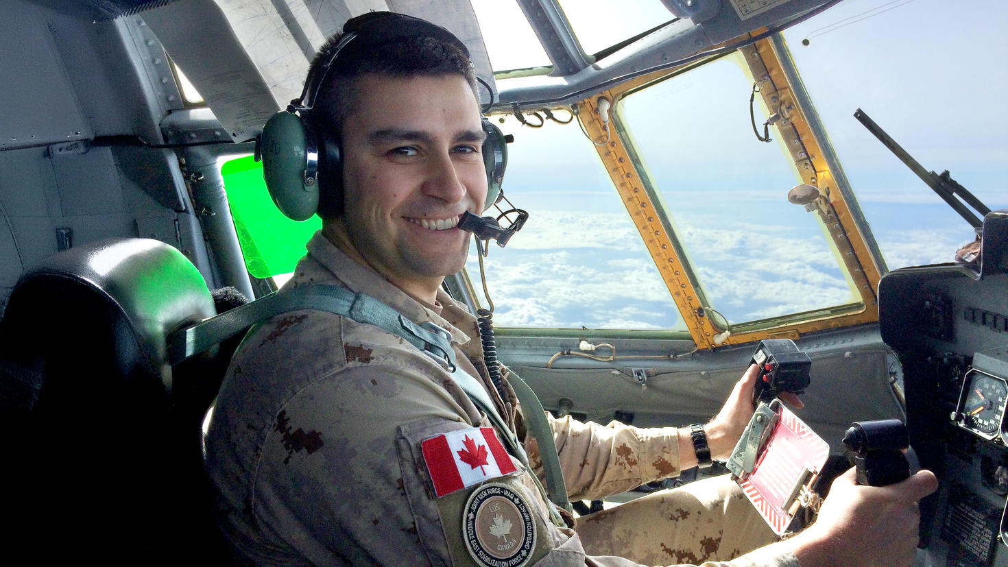 Une personne assise dans le cockpit d’un avion, en uniforme militaire.