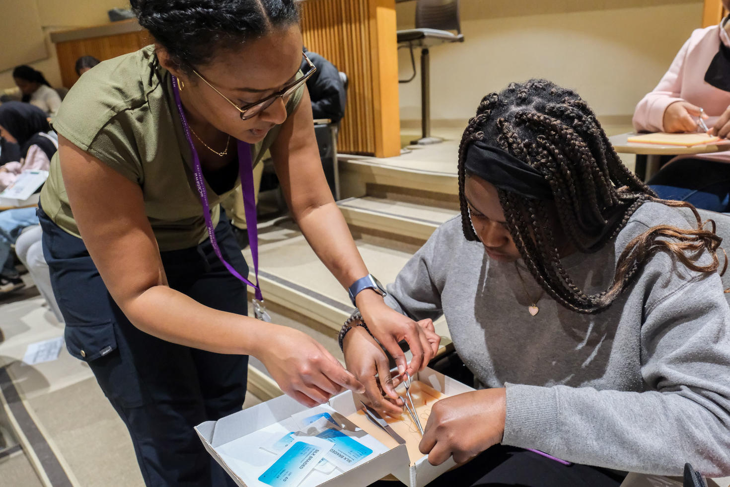 Une personne professionnelle de la santé aidant une personne étudiante à pratiquer des techniques de suture.